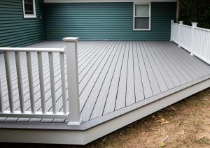New composite deck on the back of a house with green vinyl siding.with whie railings.