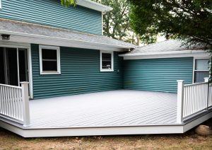 A new deck is installed on the back of a house with composite material and white hand rails.